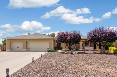 Geniş bir garaj yolu olan güzel bir ev ve önünde zarif bir şekilde duran birkaç ağaç, doğal gölgeler sunuyor ve manzarayı güzelleştiriyor.