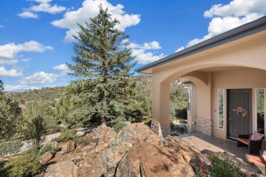 Büyüleyici bir ev engebeli, kayalık bir tepenin üzerine tünemiş, yemyeşil ağaçlar arka planda güzel bir zemin sağlıyor.