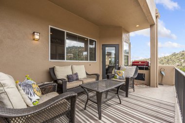 Rahat bir kanepe, birkaç sandalye ve hoş toplantılar ve rahatlama için büyüleyici bir masa ile döşenmiş rahat bir teras.