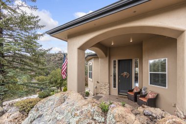 Hoş bir sundurması ve rahatlamak için önüne konmuş rahat sandalyeleri olan büyüleyici bir ev.