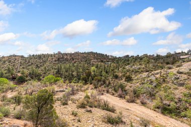 Bir hava manzarası, geniş ve kurak bir çöl manzarasını aşan ve doğanın güzelliğini gözler önüne seren dolambaçlı toprak yolu yakalar.