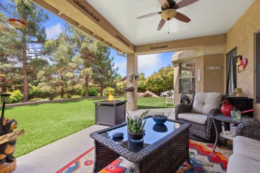 Konforlu oturma odasında şık bir masa, rahat sandalyeler ve rahat bir atmosfer için bir tavan vantilatörü var.