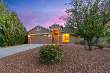 Güzel bir garaj yolu ve önünde zarif bir şekilde duran ağaçlarla dolu büyüleyici bir ev kaldırımını güzelleştiriyor.