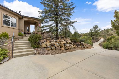 Girişine çıkan merdivenleri olan güzel bir ev ve önünde duran güzel bir ağaç var.