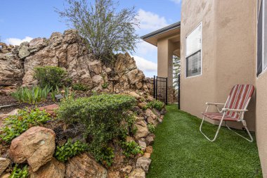 Canlı kırmızı ve beyaz bir sandalye stratejik olarak manzarayı güzelleştiren büyüleyici bir evin önündeki yemyeşil çimenlere yerleştirilir.