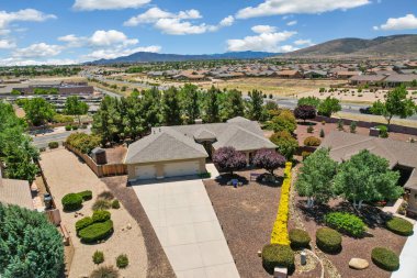 Geniş bir garaj yolu olan güzel bir ev ve önünde zarif bir şekilde duran birkaç ağaç, doğal gölgeler sunuyor ve manzarayı güzelleştiriyor.