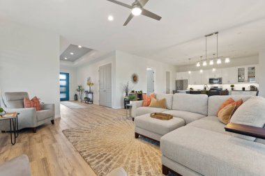 Çeşitli mobilyalarla dolu rahat bir oturma odası ve ek konfor ve stil için tavan vantilatörü.