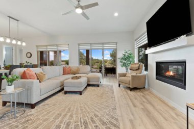 Geniş oturma odasında rahat bir kanepe, şık bir masa ve havanın uzayda güzel akmasını sağlayacak ferahlatıcı bir tavan vantilatörü var.