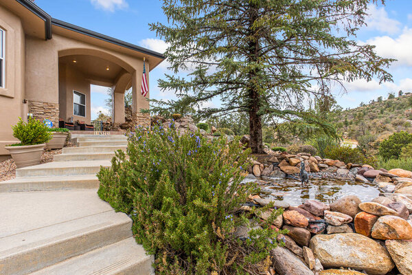There is a lovely house that has stairs leading up to its entrance and a beautiful tree standing right in front of it