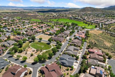 Havadan bakıldığında, arka planda zarif bir şekilde uzanan güzel bir golf sahası tarafından geliştirilmiş, pitoresk bir yerleşim yeri görünüyor.