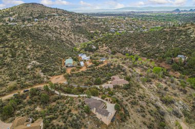 Geniş bir hava manzarası, verimli ağaçlar ve canlı bitkilerle çevrili bir tepenin üzerinde zarif bir şekilde tünemiş resimli bir ev yakalar.