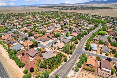 Geniş bir yerleşim alanı yakalayan bir hava manzarası. Birçok ağaçla dolu verimli bir arazide sayısız ev sergileniyor.
