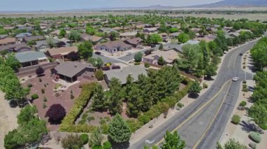 Geniş bir garaj yolu olan güzel bir ev ve önünde zarif bir şekilde duran birkaç ağaç, doğal gölgeler sunuyor ve manzarayı güzelleştiriyor.