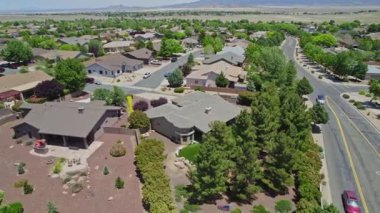 Geniş bir garaj yolu olan güzel bir ev ve önünde zarif bir şekilde duran birkaç ağaç, doğal gölgeler sunuyor ve manzarayı güzelleştiriyor.