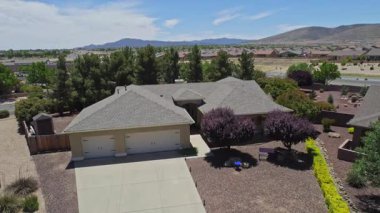 Geniş bir garaj yolu olan güzel bir ev ve önünde zarif bir şekilde duran birkaç ağaç, doğal gölgeler sunuyor ve manzarayı güzelleştiriyor.