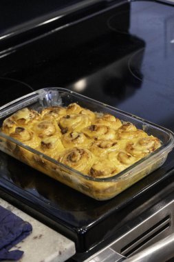 Altın tarçınlı çörekler cam tabakta, aromatik taze tarçınlı çörekler sıcak mutfak ortamında