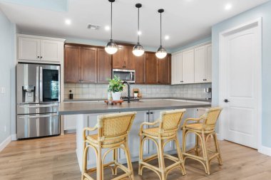 Zarif paslanmaz çelik aletler, zarif ahşap dolaplar ve işlevselliği artıran geniş bir ada içeren modern bir mutfak.