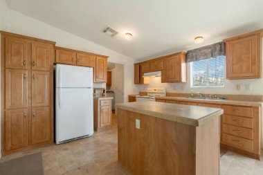 Zarif ahşap dolaplar ve modern bir dokunuş ve işlevsel alan için parlak beyaz bir buzdolabı içeren güzel tasarlanmış bir mutfak.