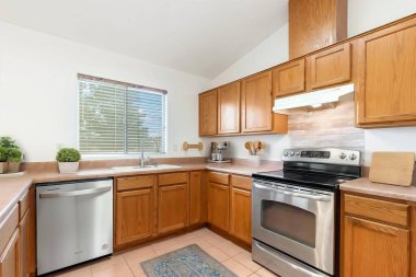 Mutfakta modern paslanmaz çelik aletler var. Güzel tasarlanmış ahşap dolaplarla tamamlanmış.