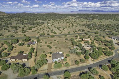 Arkaplanda dağınık ağaçlar ve parlak mavi bir gökyüzünün olduğu geniş ve geniş bir alan.