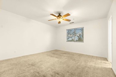 Tavan vantilatörü ve penceresi olan boş bir yatak odası var. Bu da doğal ışığın içeri süzülmesini sağlıyor ve sakin bir atmosfer yaratıyor.