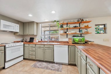 Tezgahın üzerine göz alıcı ve canlı bir dokunuş için zarif bir şekilde yerleştirilmiş bir akvaryum içeren güzel tasarlanmış bir mutfak.