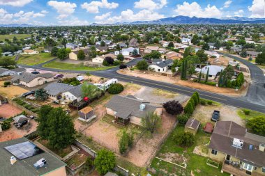 Canlı bir yerleşim bölgesinin geniş bir hava manzarası, çeşitli ağaçlar ve yeşilliklerle çevrili çok sayıda evi gösteriyor.