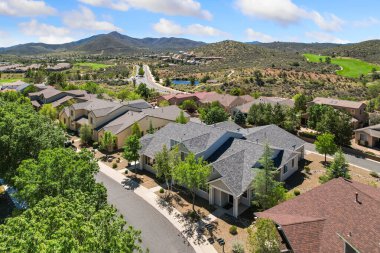 Bu görüntü, arka planda görkemli dağlar olan huzurlu evlerin gururla sergilendiği pitoresk yerleşim yerlerinin havadan görüntüsünü yakalıyor.