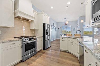 Bu mutfak modern paslanmaz çelik aletlerle mükemmel eşleştirilmiş zarif beyaz dolaplar içeriyor, şık ve işlevsel bir alan yaratıyor.