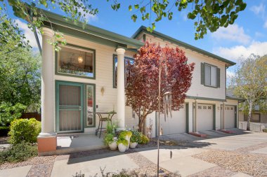 Önünde yüksek bir ağaç bulunan geniş ve büyük beyaz bir ev manzaralı bir konut manzarası yaratıyor.