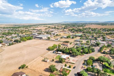Sersemletici hava görüntüleri banliyö manzarasını evlerle, yeşil yapraklarla ve mavi gökyüzünün altındaki açık alanlarla gösteriyor..