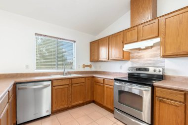 Zarif ahşap dolaplarla eşleştirilmiş modern paslanmaz çelik aletlerin yer aldığı çok güzel tasarlanmış bir mutfak.