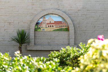 Yapısına güzelce entegre edilmiş büyüleyici bir evi tasvir eden canlı bir tablonun yer aldığı sağlam, iyi inşa edilmiş bir tuğla duvar.