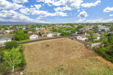 Geniş bir hava manzarası, sayısız ev ve manzarayı noktalayan yemyeşil ağaçlarla dolu canlı bir yerleşim alanı gösteriyor.