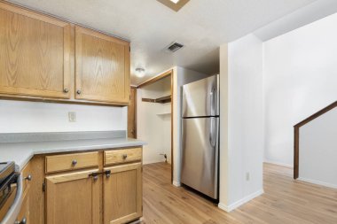 Modern paslanmaz çelik bir buzdolabıyla eşleştirilmiş zarif ahşap dolapları olan güzel tasarlanmış bir mutfak stil ve işlevselliğin mükemmel bir karışımını oluşturuyor.