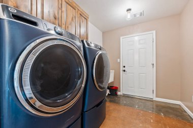 Çamaşır odasında iki mavi yıkama ve kurutma makinesi var. Çamaşırları etkili ve etkili bir şekilde yıkamak için işlevsel bir alan yaratıyorlar.