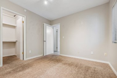 Yatak odasında mobilya yok ve bir dolap ve doğal ışığın boşluğa girmesine izin veren bir pencere var.