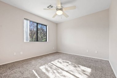 İçinde pencere, tavan vantilatörü ve lüks halı bulunan parlak ve havadar bir yatak odası. Rahatlamak ya da üretkenlik için mükemmel.