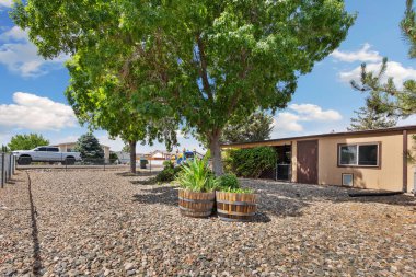 Önünde zarif bir şekilde duran ve manzarayı güzelleştiren bir ağaçla tamamlanmış çakıllı bir garaj yolu olan büyüleyici bir ev var.