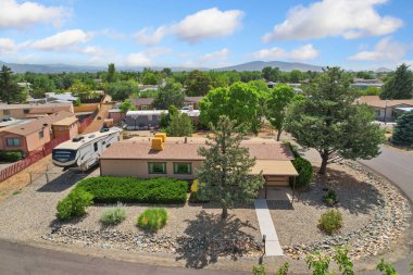 Tam önünde park etmiş bir araçla birlikte bir evi gösteren hava manzarası, çevre alanı ve özelliklerini vurguluyor.