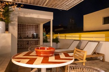 Üzerinde dekoratif bir kâse ve rahat sandalyelerle çevrili iyi tasarlanmış bir masa bulunan güzel bir teras alanı.