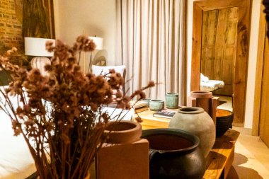 Canlı çiçeklerle dolu güzel bir vazo zarif bir masada, sıcak ve davetkar bir oturma odasında oturuyor.