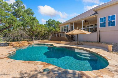 Önünde geniş bir yüzme havuzu bulunan geniş ve güzel tasarlanmış bir ev lüks bir ortam yaratıyor.