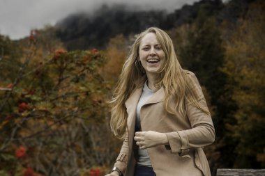 Doğadan zevk alan sıradan bir kadın, sonbahar bahçesinde mevsimsel titreşimleri kucaklayan mutlu bir bayan.