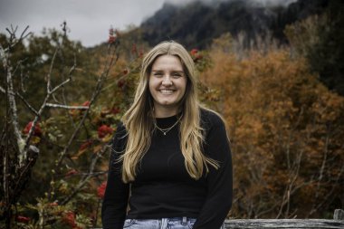 Neşeli bir sonbahar arkaplanı olan mutlu bir kadın, güz manzarasının keyfini çıkaran kendine güvenen bir kadın.