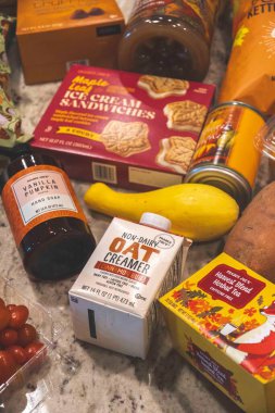 Mutfak tezgahına serpiştirilmiş çeşitli canlı market eşyaları, atıştırmalıklar, sebzeler ve içecekler dahil..