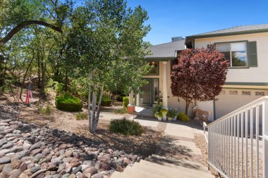 Sağlam çitleri olan, önünde gururla duran ve cazibesini artıran güzel ağaçları olan büyüleyici bir ev.