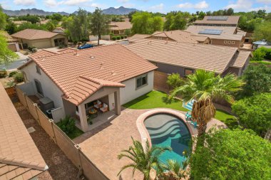 Mülkün arka bahçesinde geniş bir havuz bulunan güzel bir evi gösteren hava manzaralı bir manzara.