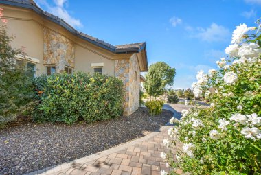 Bahçe Yolu, Stucco cephesi ve Beyaz Güllerle kaplı Paver Yolu ile Günışığı Akdeniz Evi