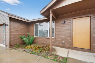 Kahverengi Kapılı Islak Giriş. Emlakçı Küçük Çiçekli ve Süslü Çalıları Göstermeye Hazırlanıyor